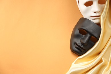 Photo of Theater arts. Two masks and golden fabric on pale orange background, top view. Space for text