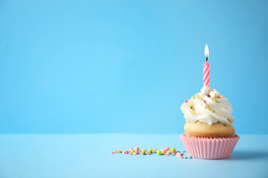 Photo of Delicious birthday cupcake with candle on light blue background. Space for text