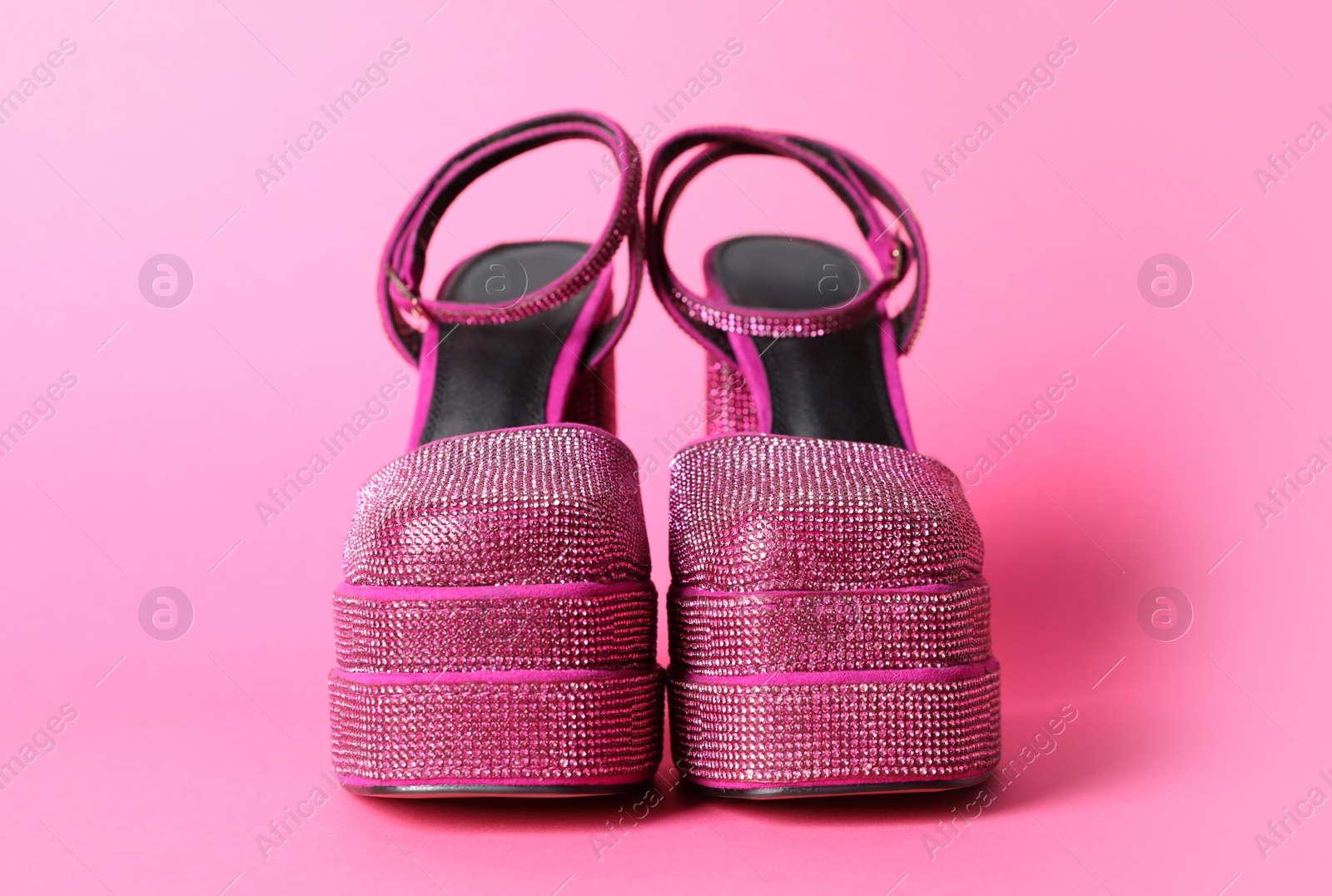 Photo of Fashionable punk square toe ankle strap pumps on pink background. Shiny party platform high heeled shoes