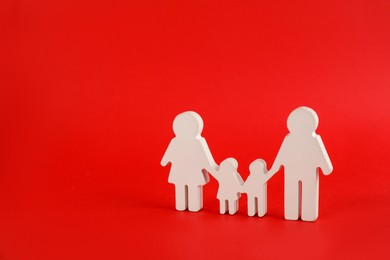 Photo of Family figure on red background, space for text. Child adoption concept