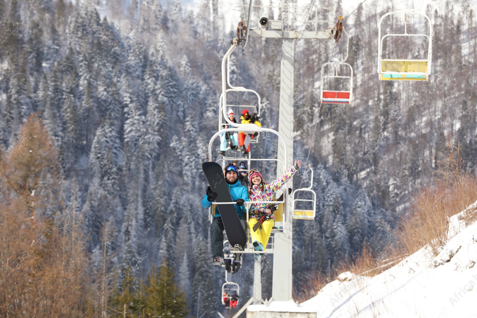 Photo of Couple using chairlift at mountain ski resort. Winter vacation