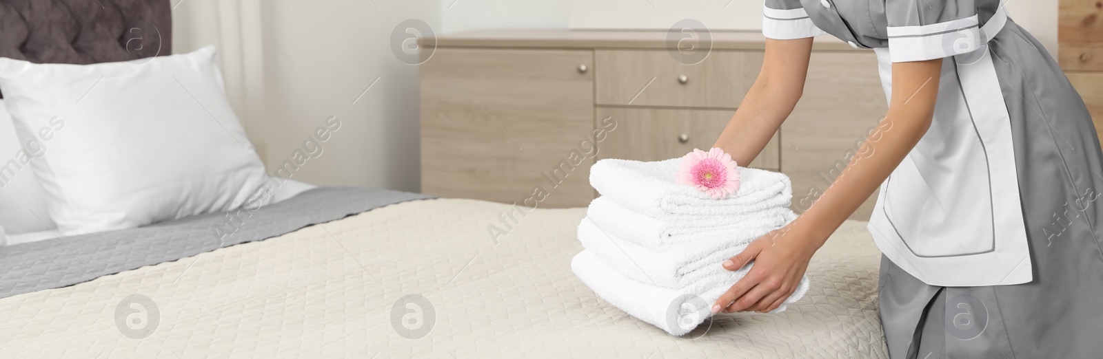 Image of Chambermaid putting fresh towels on bed in hotel room, closeup view with space for text. Banner design
