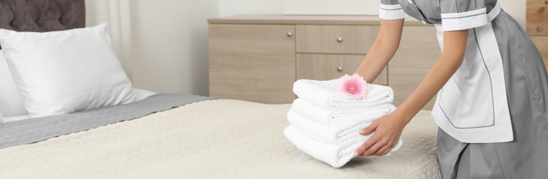 Image of Chambermaid putting fresh towels on bed in hotel room, closeup view with space for text. Banner design