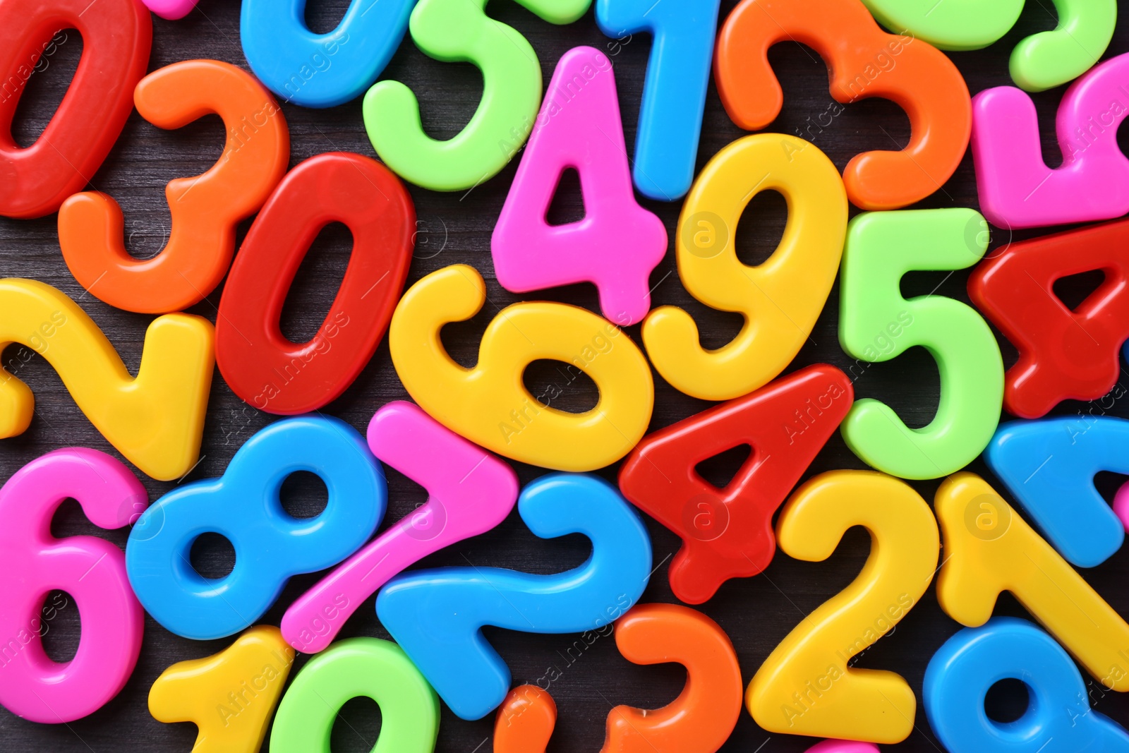 Photo of Colorful numbers on dark wooden school desk, top view