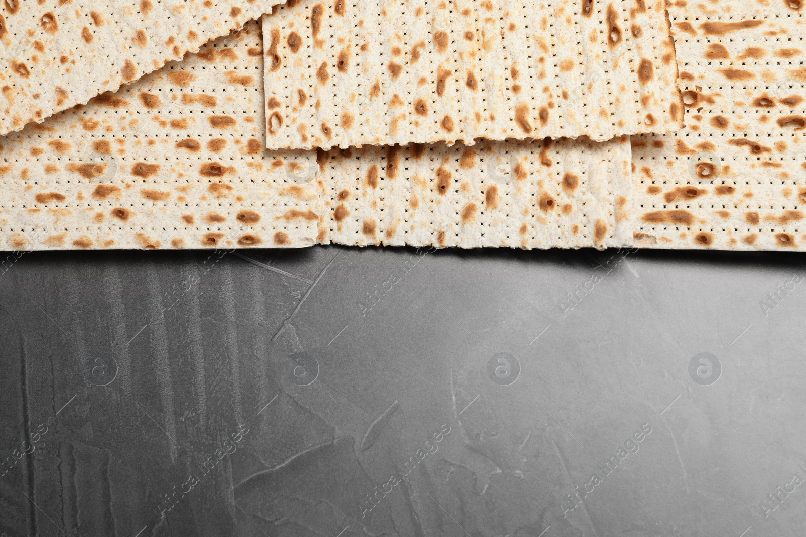 Photo of Traditional matzos on grey table, flat lay. Space for text