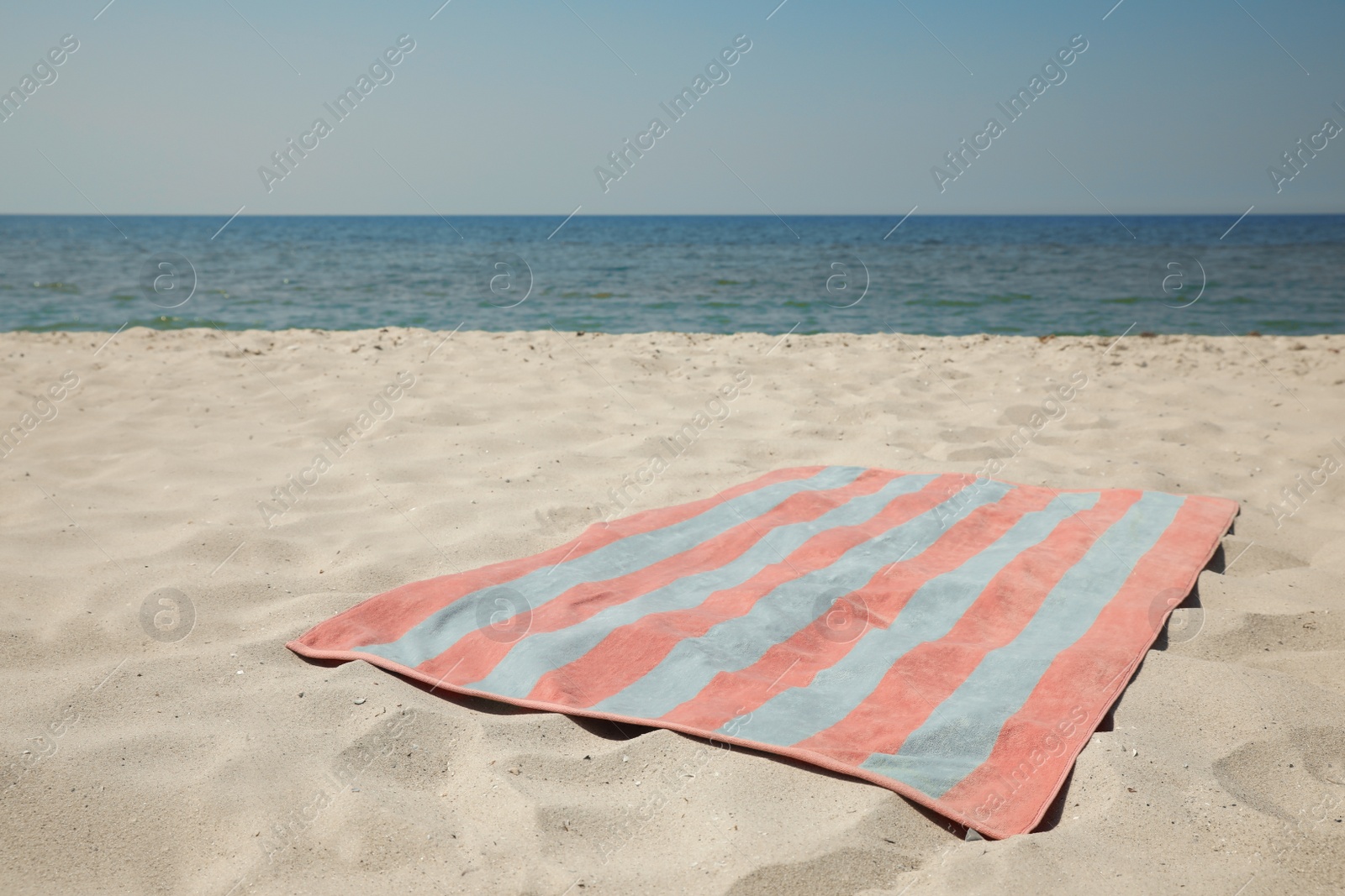 Photo of Striped beach towel on sand near sea