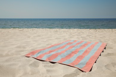 Photo of Striped beach towel on sand near sea