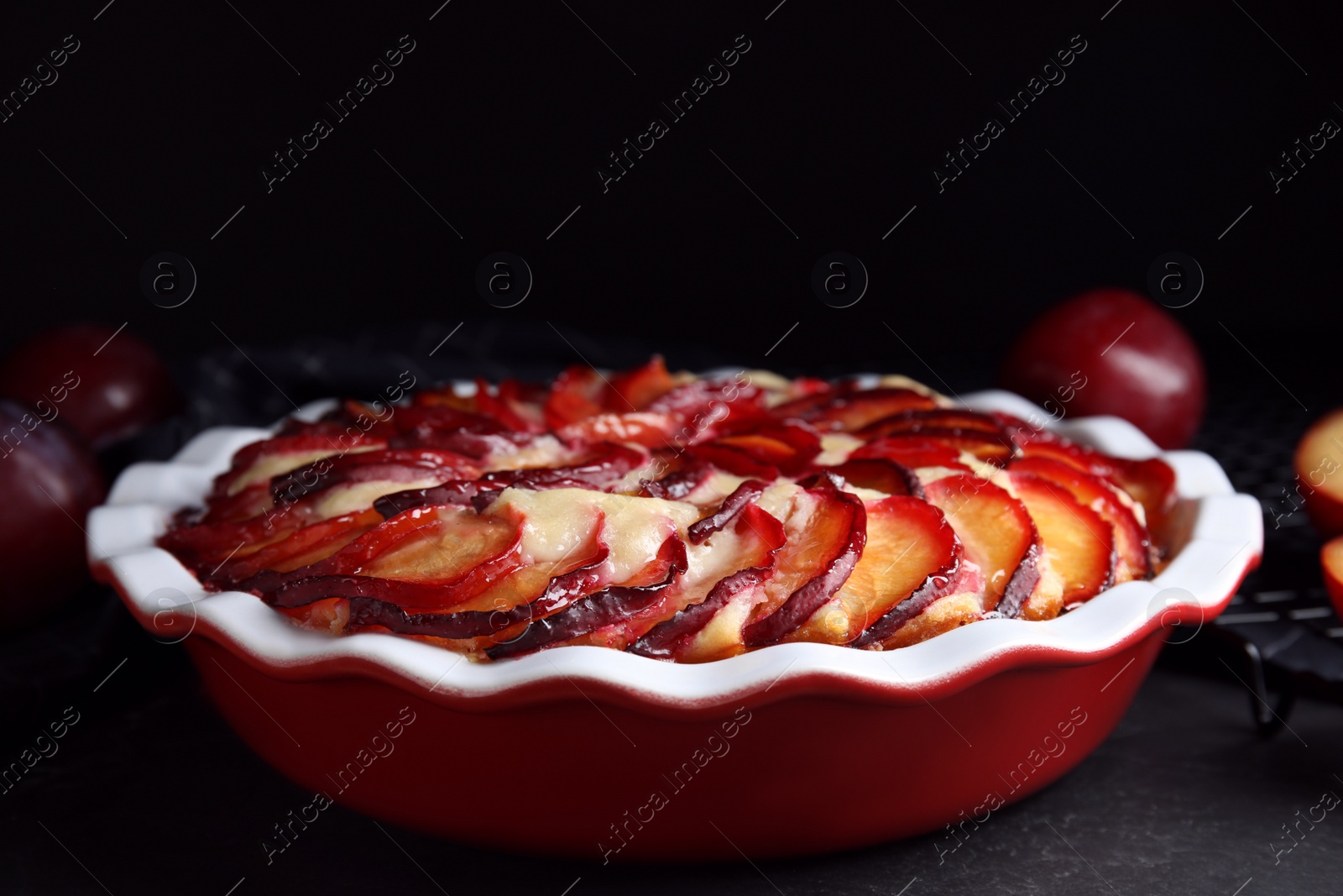 Photo of Delicious cake with plums on black table, closeup