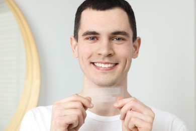 Photo of Young smiling man with whitening strips indoors