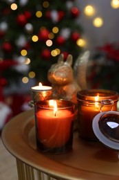 Burning candles on table in room decorated for Christmas