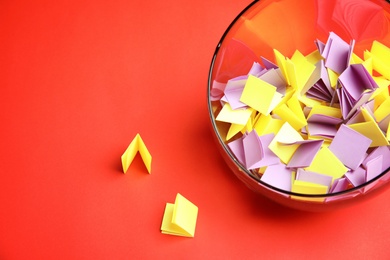 Photo of Paper pieces for lottery in glass vase on color background. Space for text