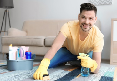 Mature man cleaning carpet at home