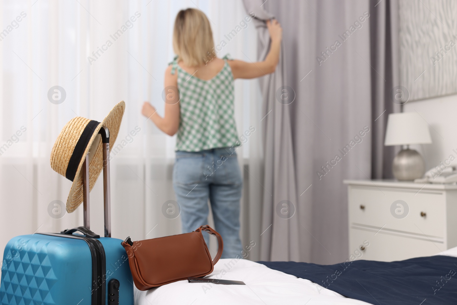 Photo of Guest opening curtains in stylish hotel room, selective focus