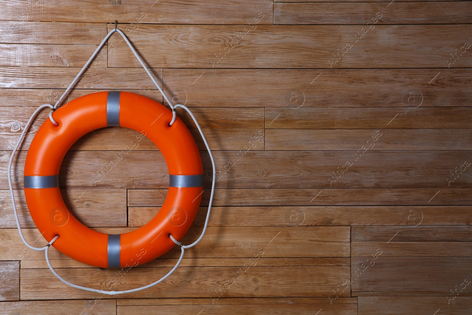 Photo of Orange lifebuoy on wooden background, space for text. Rescue equipment