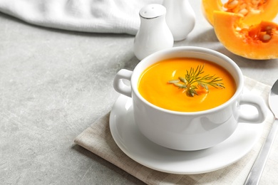 Delicious pumpkin cream soup in bowl on light table. Space for text