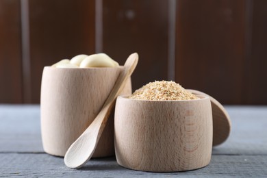 Photo of Dehydrated garlic granules, fresh cloves and spoon on grey wooden table, closeup