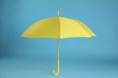 Photo of Stylish open yellow umbrella on light blue background