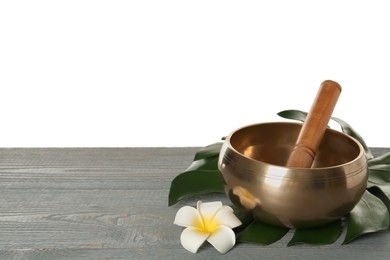 Photo of Golden singing bowl, mallet, leaf and flower on grey wooden table against white background, space for text