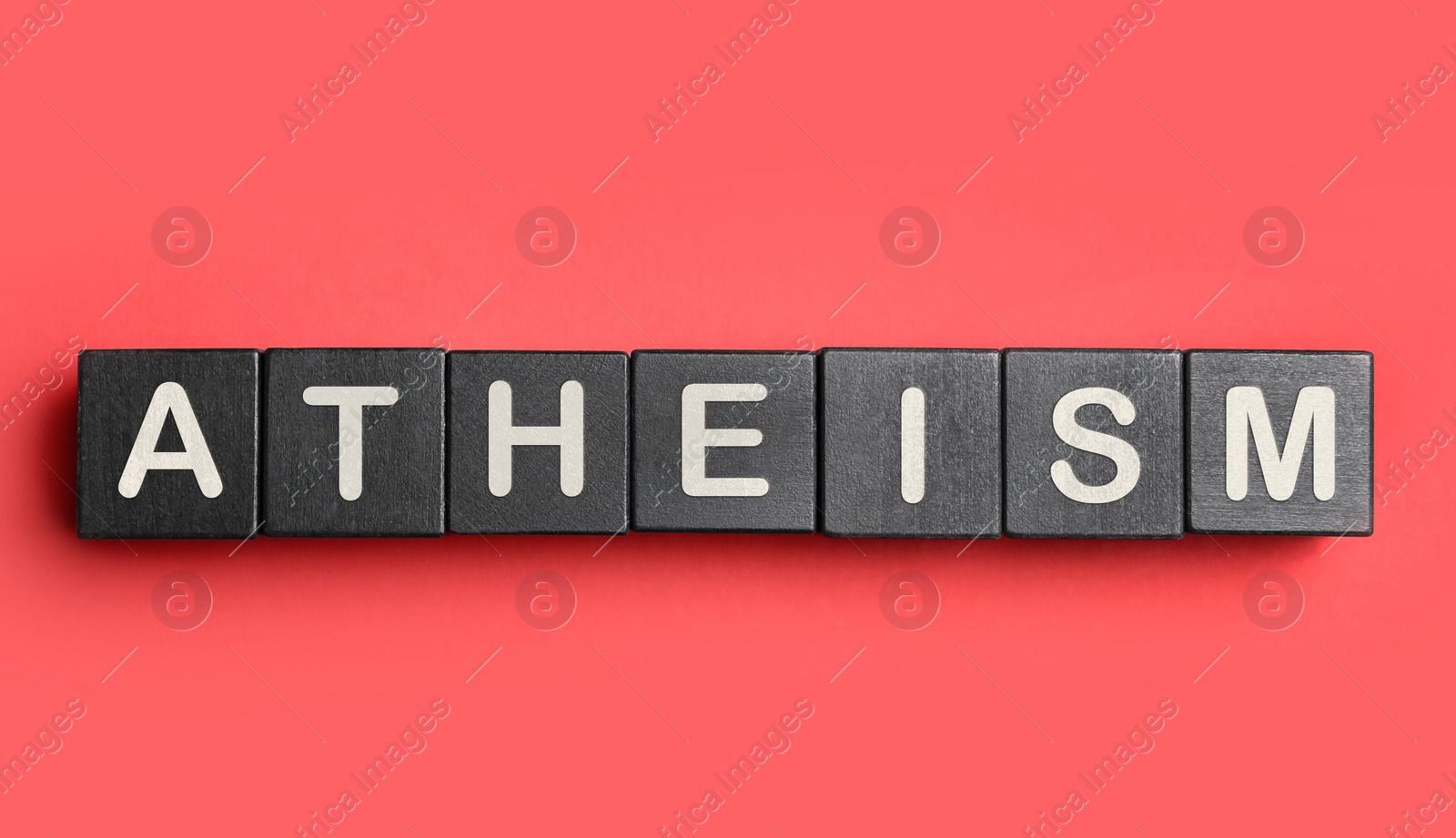 Image of Word Atheism made of black wooden cubes with letters on red textured table, top view