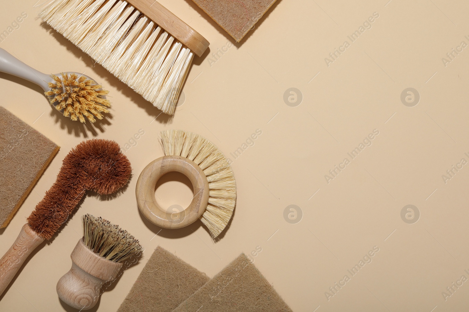 Photo of Cleaning brushes and sponges on beige background, flat lay. Space for text