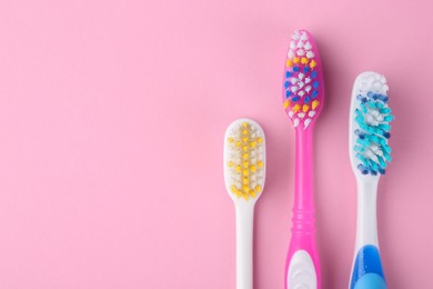 Photo of Many different toothbrushes on pink background, flat lay. Space for text