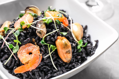 Photo of Delicious black risotto with seafood in bowl on table, closeup