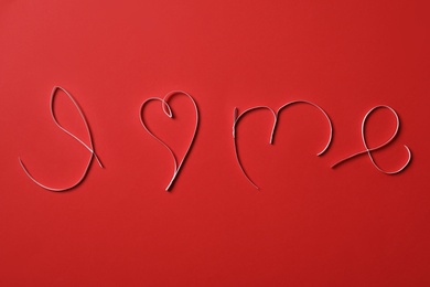 Photo of Phrase I Love Me made with paper strips on red background, flat lay