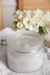 Photo of Jar of natural exfoliating salt scrub on white towel