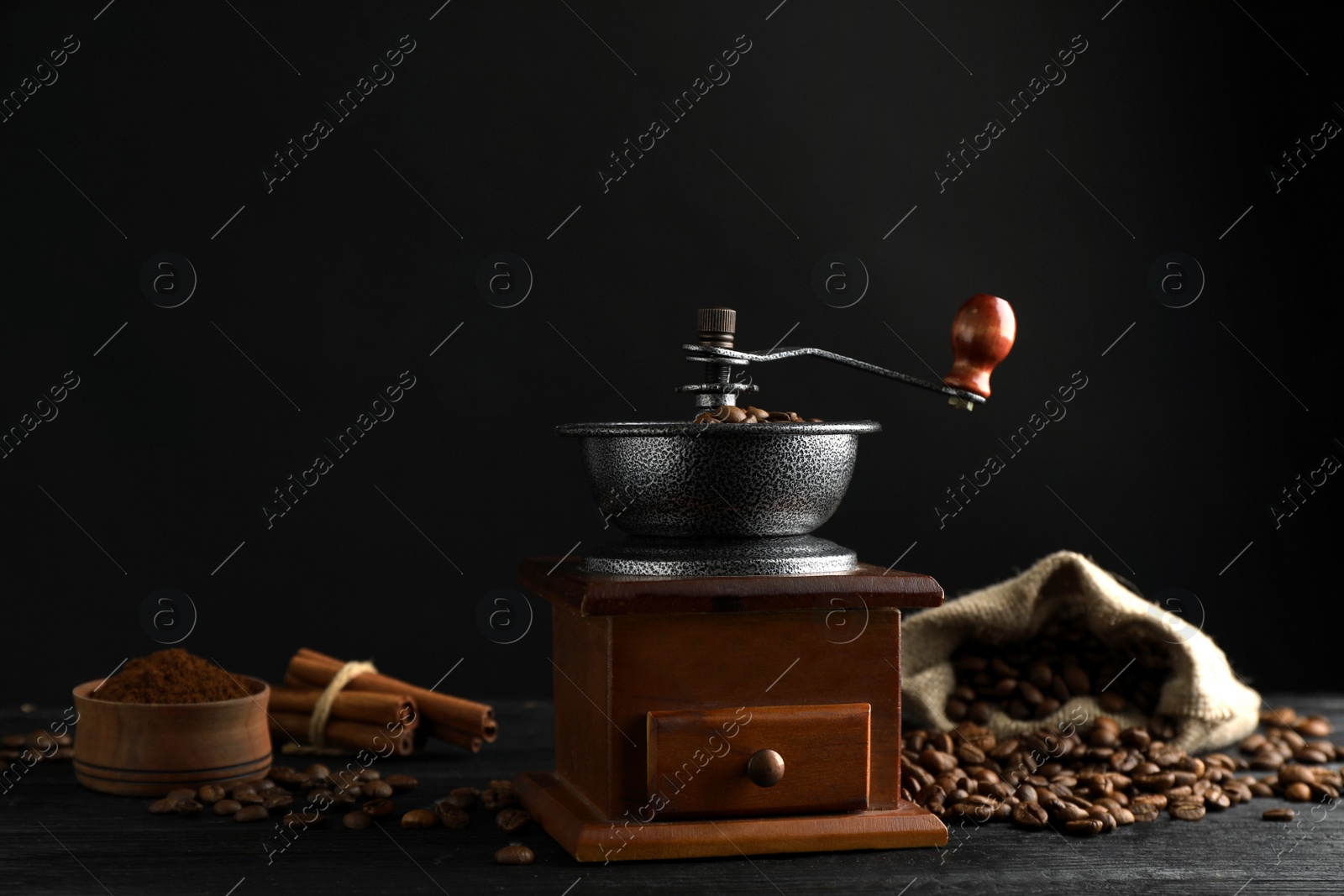 Photo of Vintage manual coffee grinder, powder and beans on black wooden table