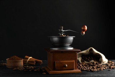 Vintage manual coffee grinder, powder and beans on black wooden table