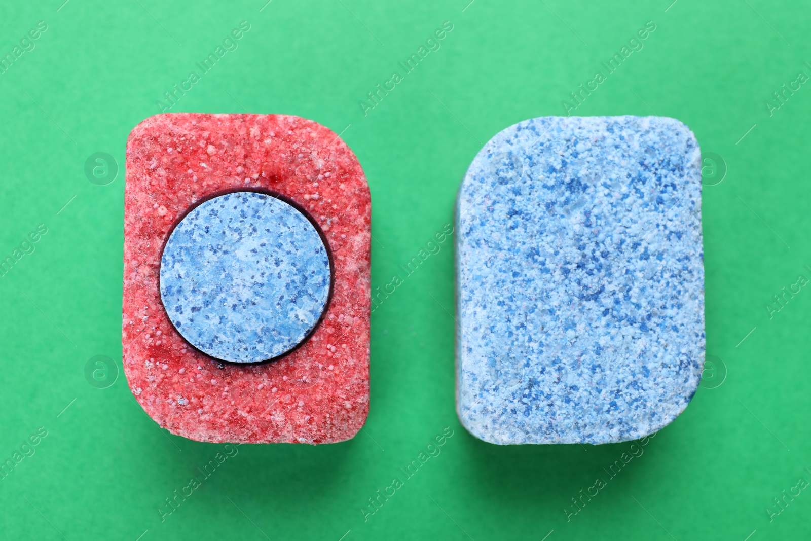 Photo of Dishwasher detergent tablets on green background, flat lay