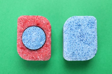 Photo of Dishwasher detergent tablets on green background, flat lay