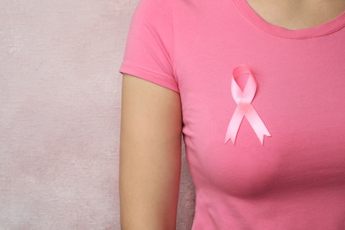 Photo of Woman with pink ribbon on color background, space for text. Breast cancer awareness