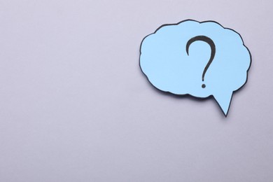 Photo of Paper speech bubble with question mark on light grey background, top view. Space for text