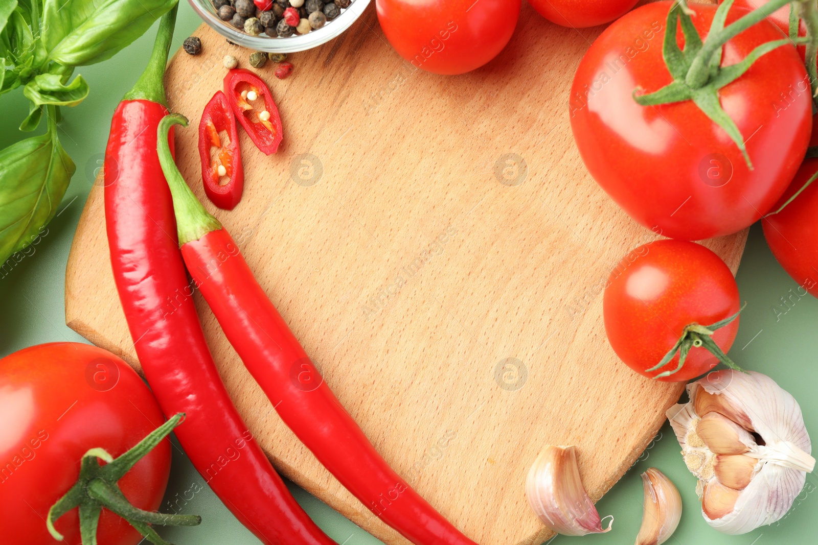 Photo of Frame made of wooden board and tasty ketchup ingredients on green table, flat lay. Space for text