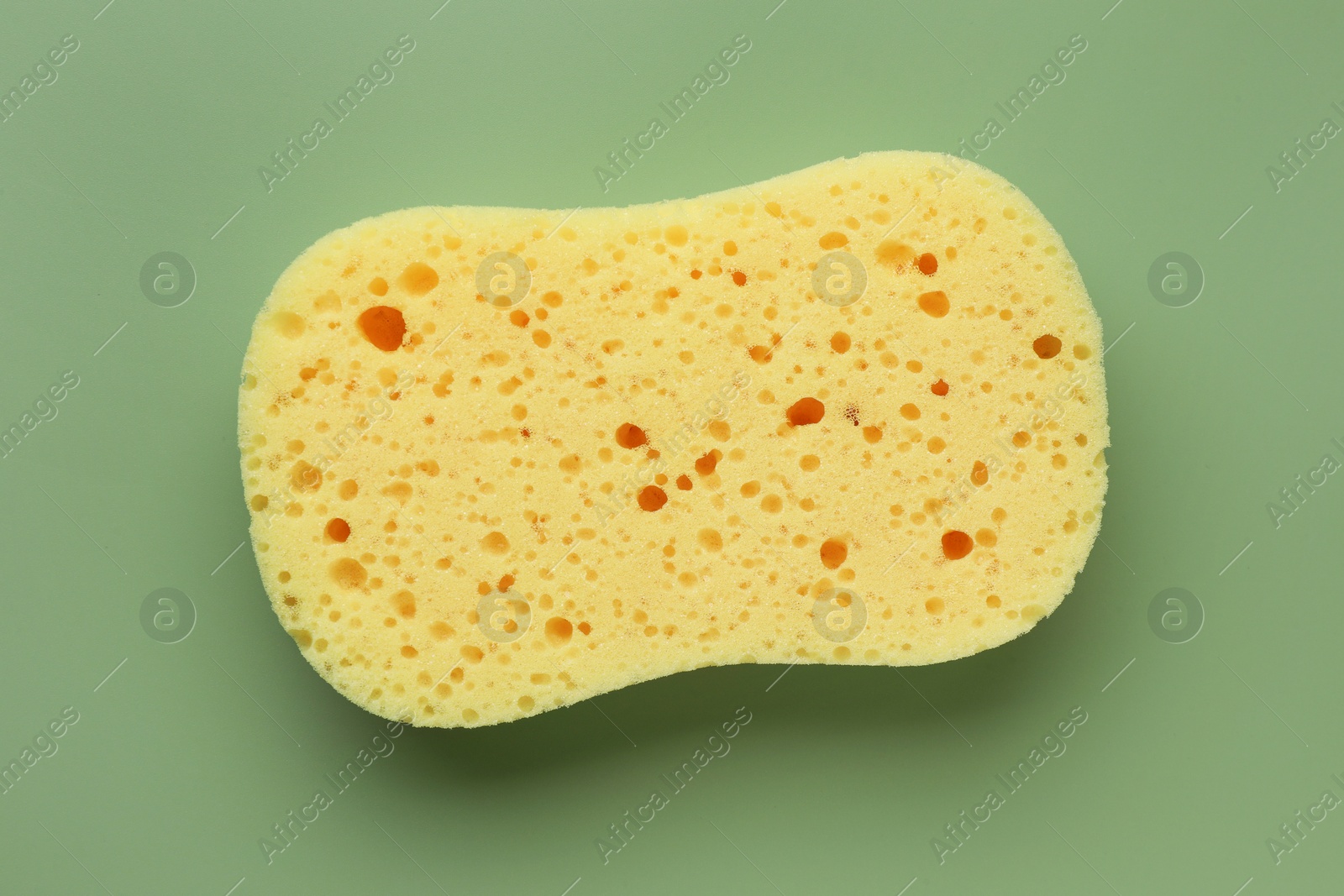 Photo of New yellow sponge on green background, top view