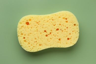 New yellow sponge on green background, top view
