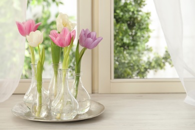 Photo of Beautiful fresh tulips on window sill indoors. Spring flowers