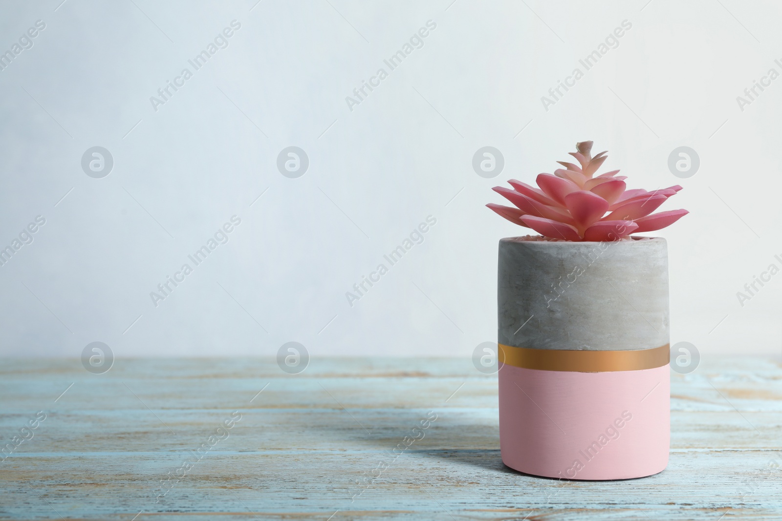 Photo of Artificial plant in flower pot on light blue wooden table. Space for text