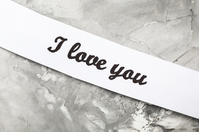 Card with text I Love You on light grey stone background, top view