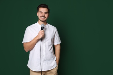 Photo of Young handsome man in casual clothes with microphone on color background. Space for text