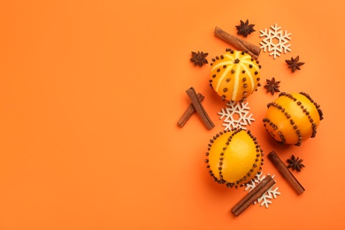 Flat lay composition with pomander balls made of fresh citrus fruits on orange background. Space for text