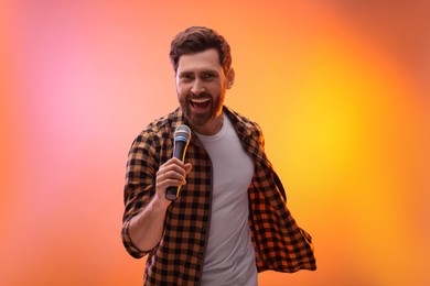 Photo of Handsome man with microphone singing in color lights