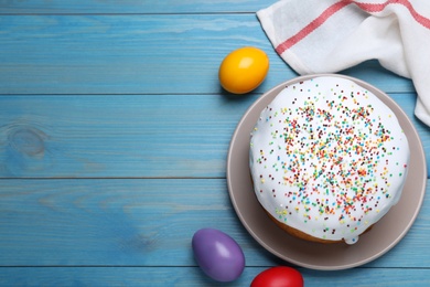 Photo of Easter cake and color eggs on blue wooden table, flat lay. Space for text