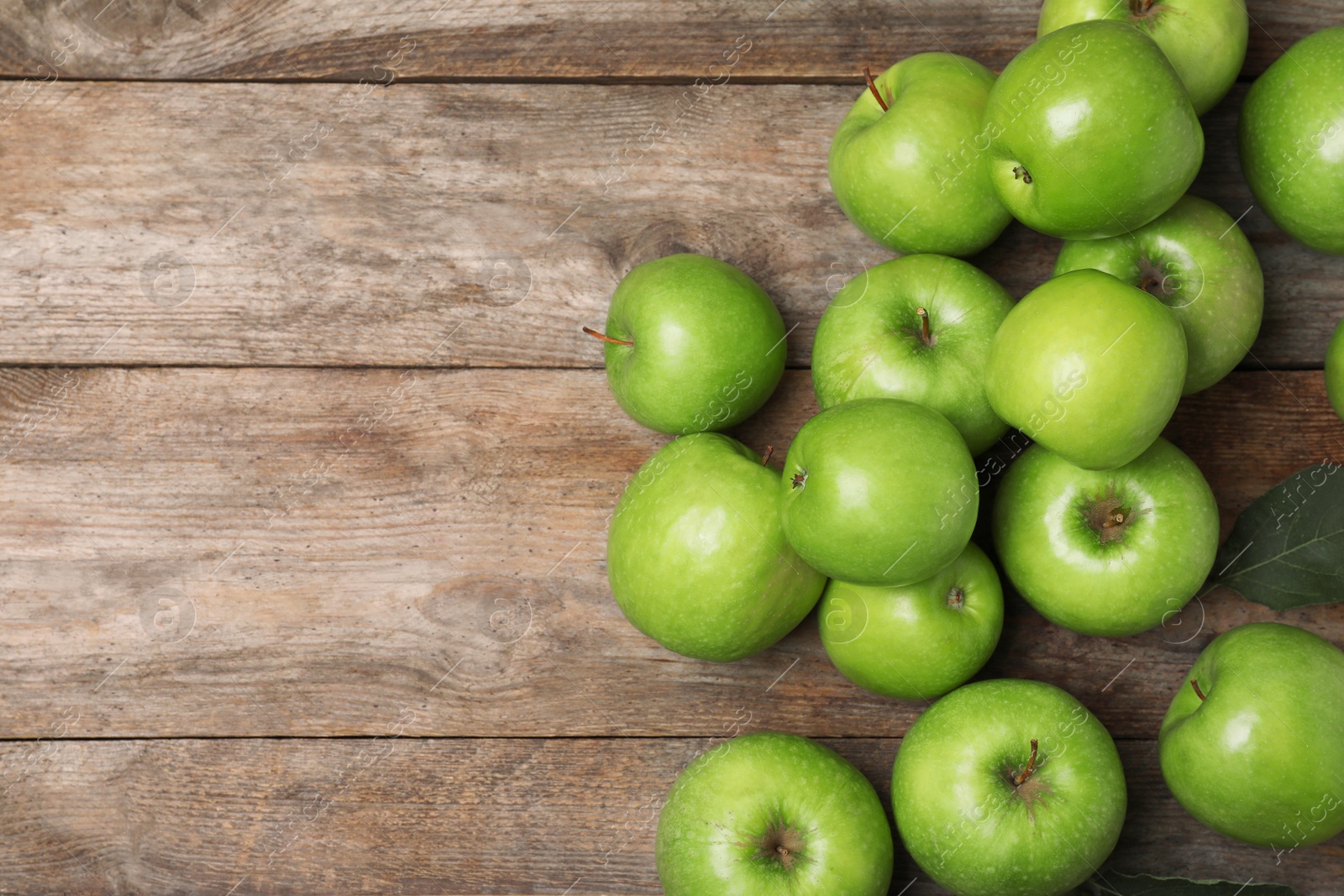 Photo of Many juicy green apples and space for text on wooden background, top view