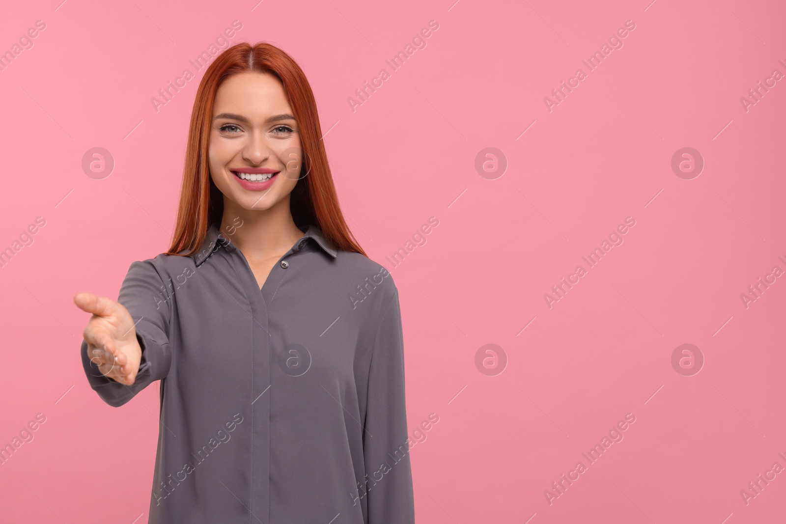 Photo of Happy woman welcoming and offering handshake on pink background, space for text