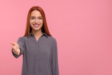 Photo of Happy woman welcoming and offering handshake on pink background, space for text