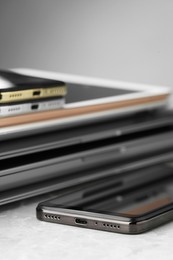 Photo of Stack of electronic devices on grey stone table, closeup
