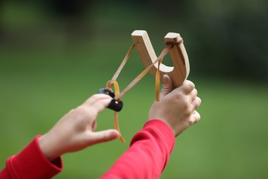 Photo of Little boy playing with slingshot outdoors, closeup