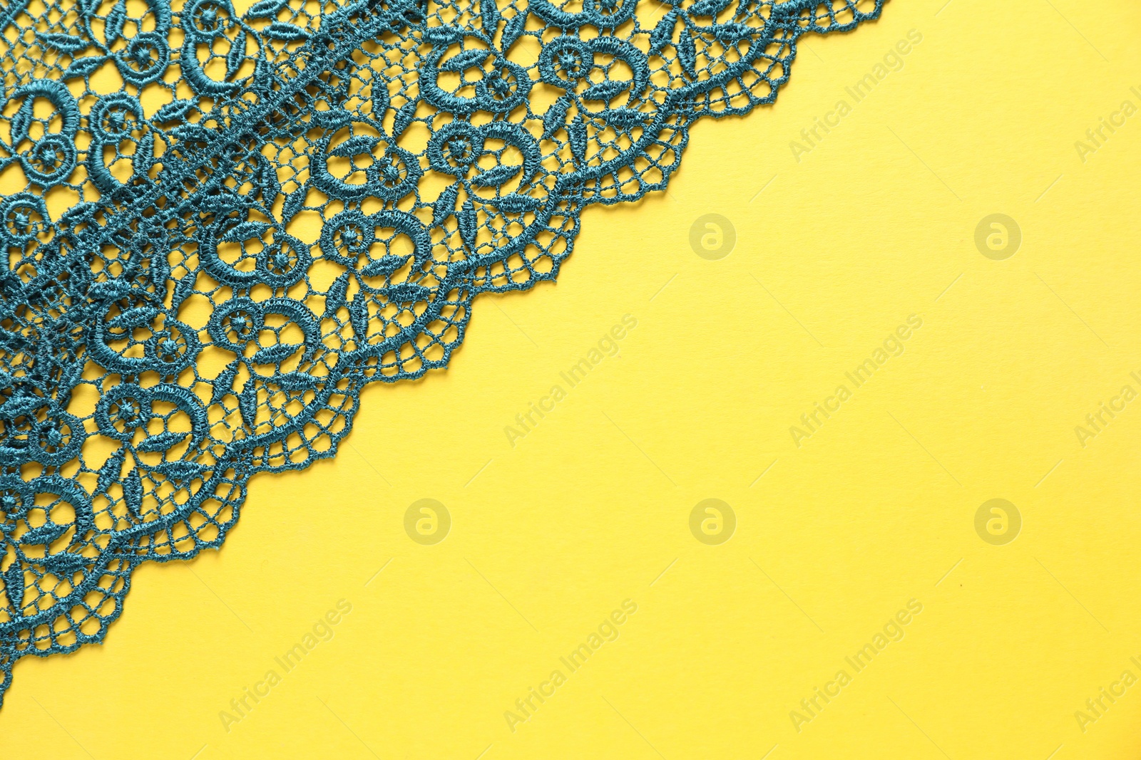 Photo of Green lace on yellow background, top view. Space for text